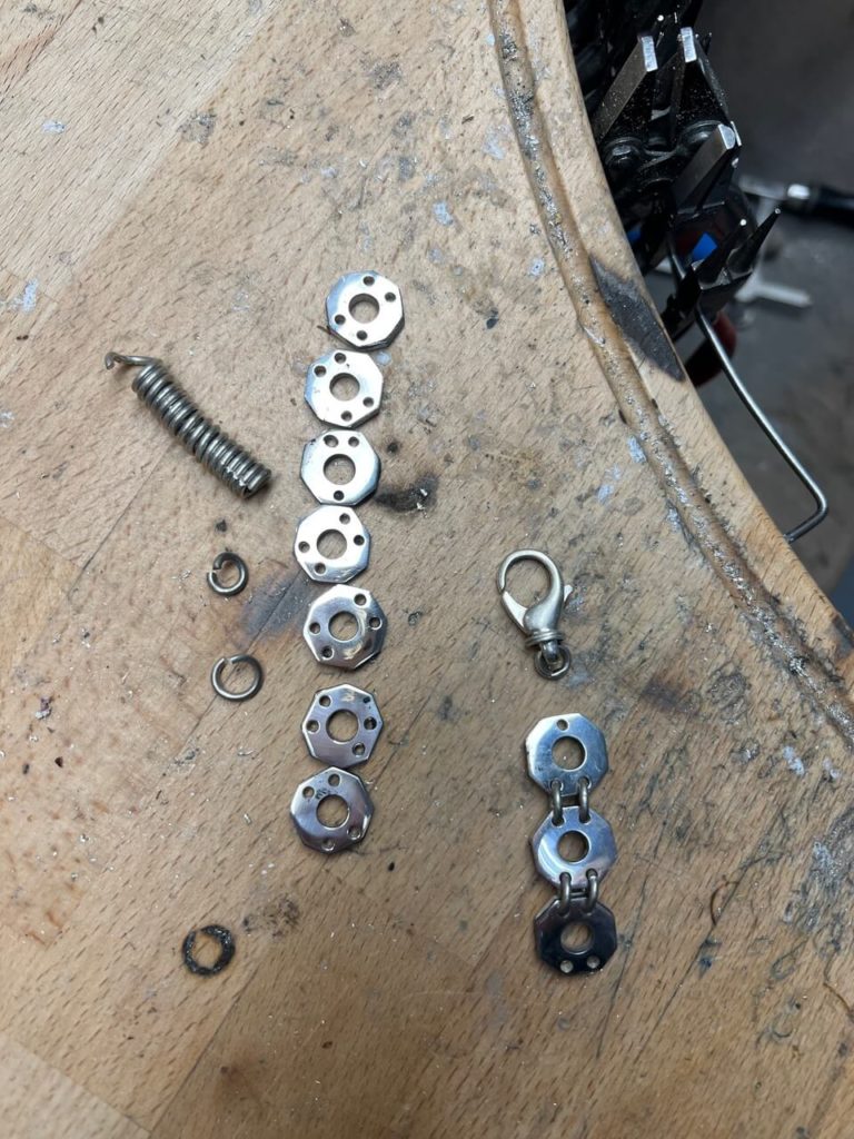 Eine Spiralfeder und mehrere sechseckige Metallelemente auf einer Werkbank.