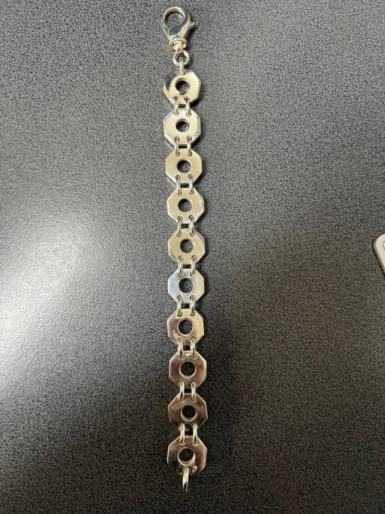 Elegantes Silberarmband mit geometrischen, achteckigen Gliedern und sicherem Karabinerverschluss, präsentiert auf einem dunklen Untergrund.