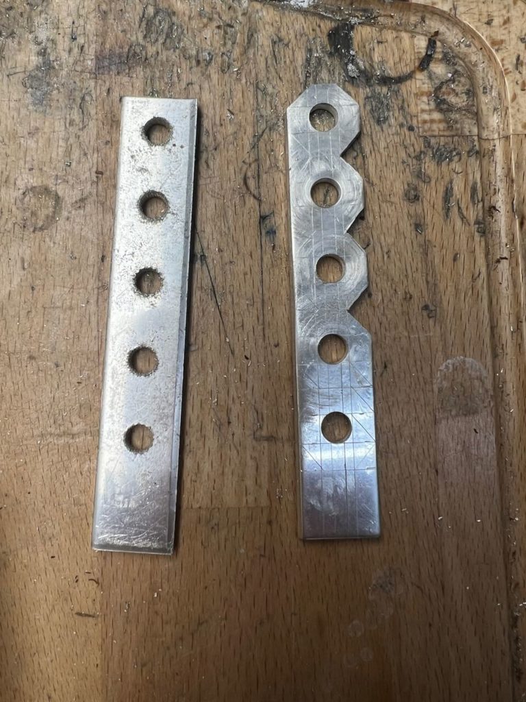 Zwei Metallstreifen mit Bohrungen auf einer Werkbank in unserer Goldschmiede in Berlin-Lankwitz, die bei Schmuckreparaturen zum Einsatz kommen.