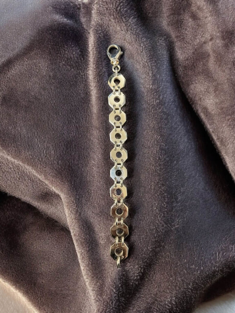 Elegantes Silberarmband mit geometrischen, achteckigen Gliedern und sicherem Karabinerverschluss, präsentiert auf einem dunklen Tuch.